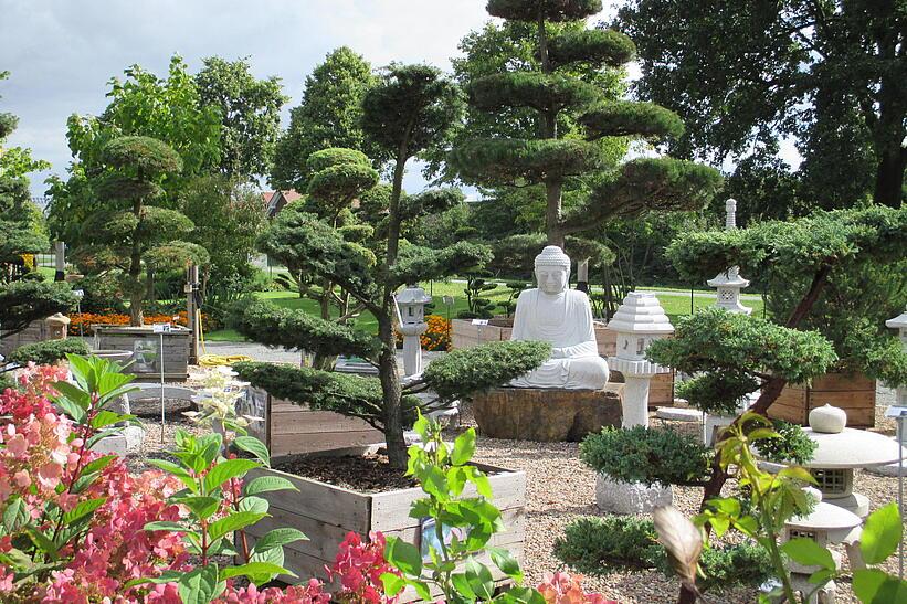 Blick in einen Garten mit einer weißen asiatischen Skulptur