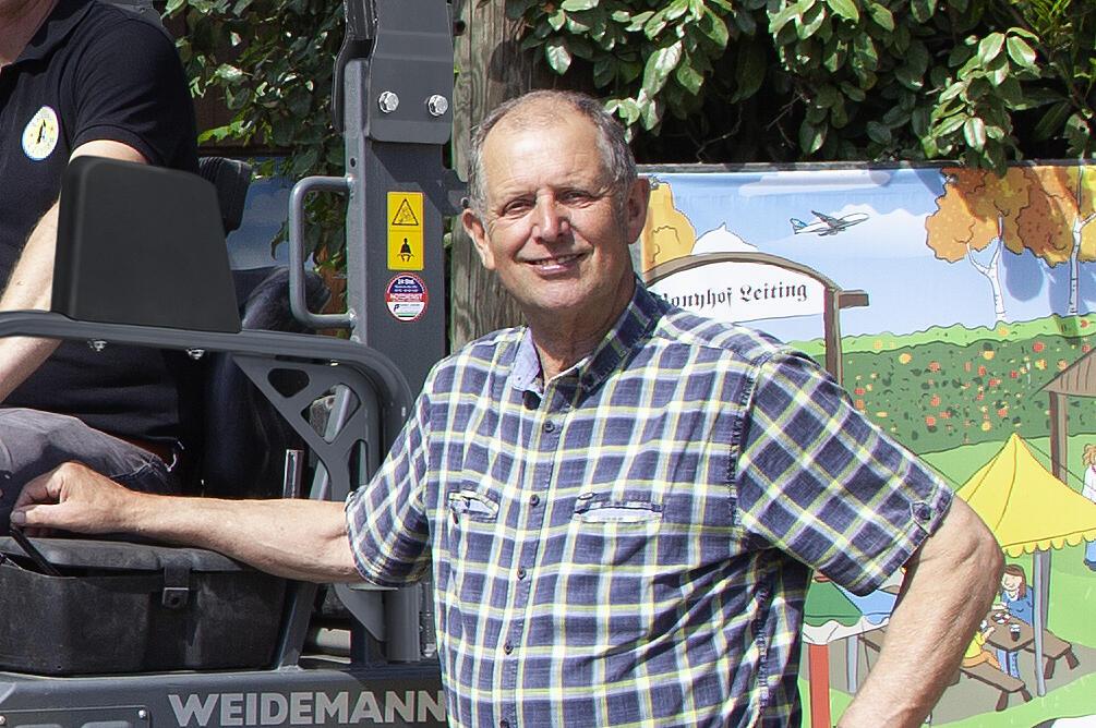 Mehrere Menschen stehen um einen Weidemann Hoftrac 1160e mit Fahrerschutzdach